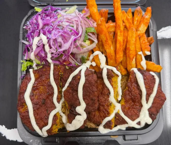 Chapli kebab platter with spiced kebab patties over seasoned rice, slaw, seasoned fries and white sauce
