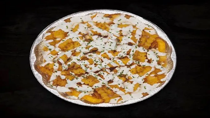 Crispy chicken over fries with white sauce and herbs