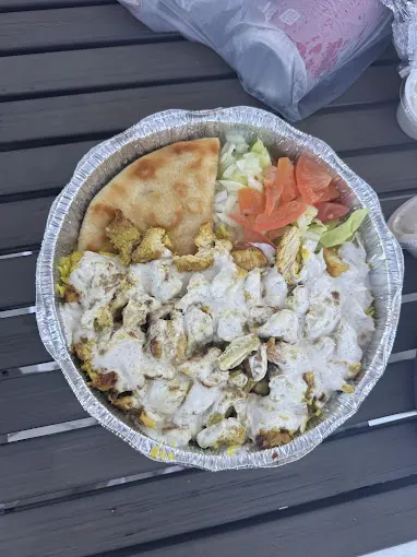 Chicken over rice smothered in white sauce with salad and pita