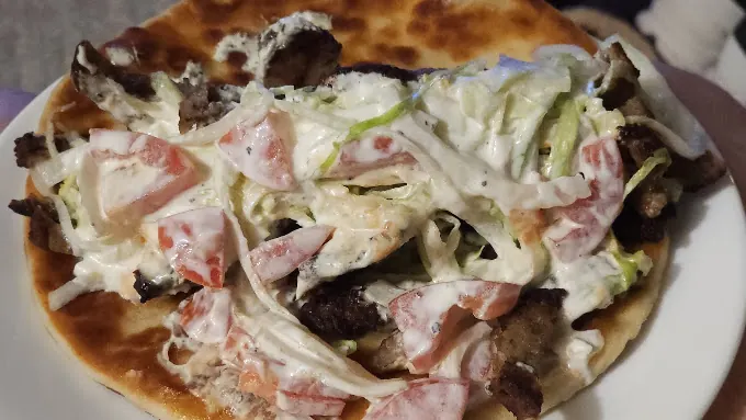 Gyro on grilled pita with lettuce, tomato and white sauce