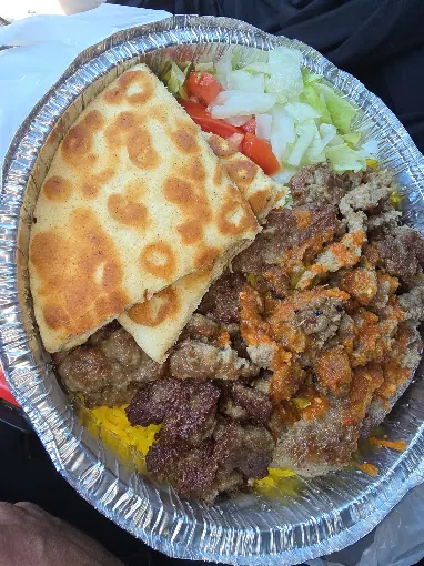 Kofta platter over rice with hot sauce, salad and pita