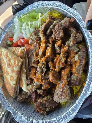 Lamb platter over yellow rice with hot sauce, salad and pita