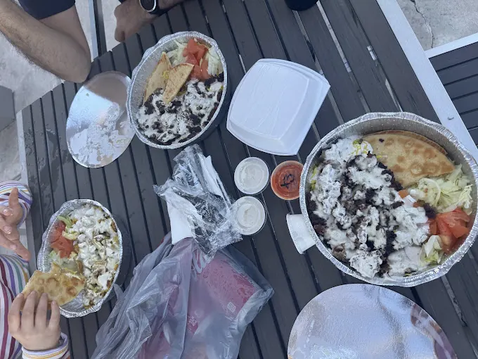 Several platters with white sauce shared on an outdoor table
