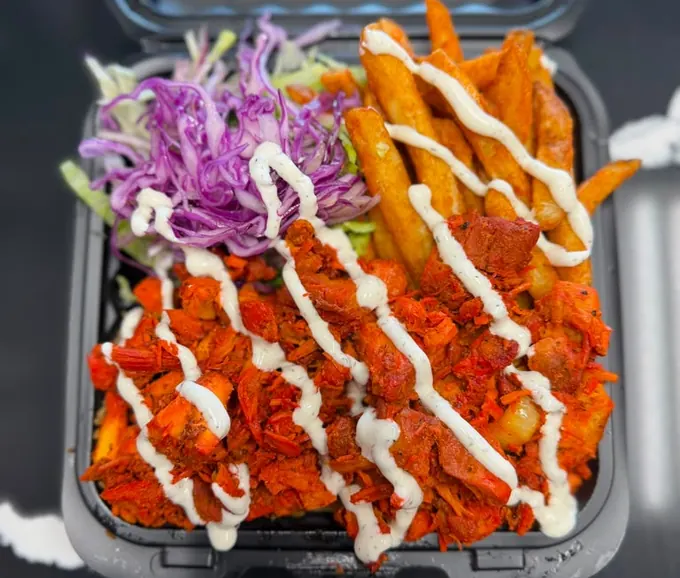 Spicy chicken platter with red-spiced chicken, seasoned fries, slaw and white sauce